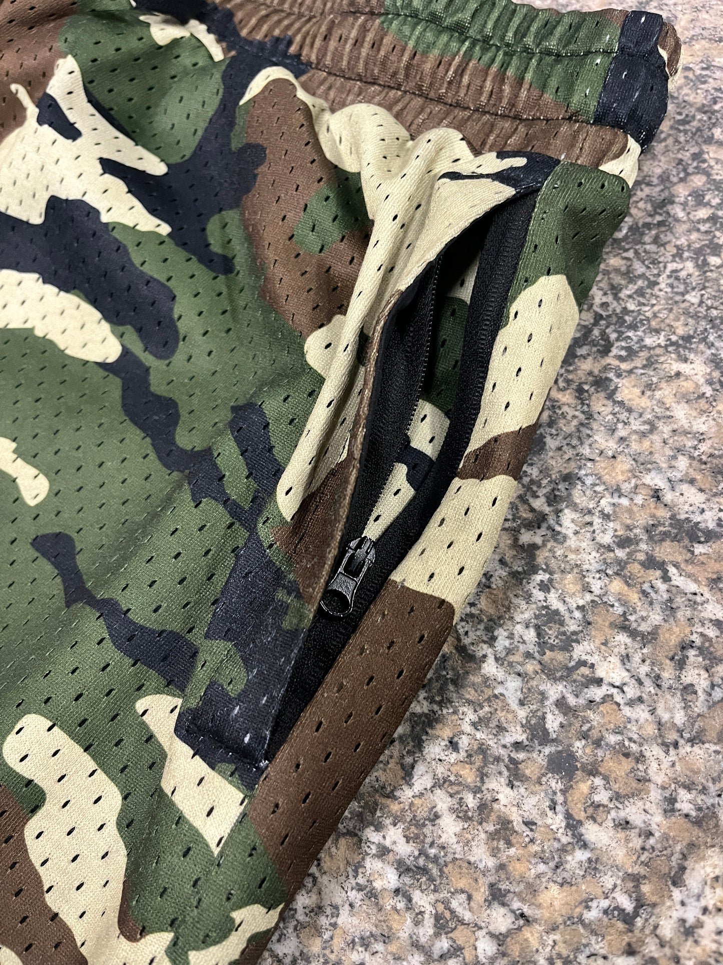 Camouflage-patterned bag with a brown strap on a textured surface