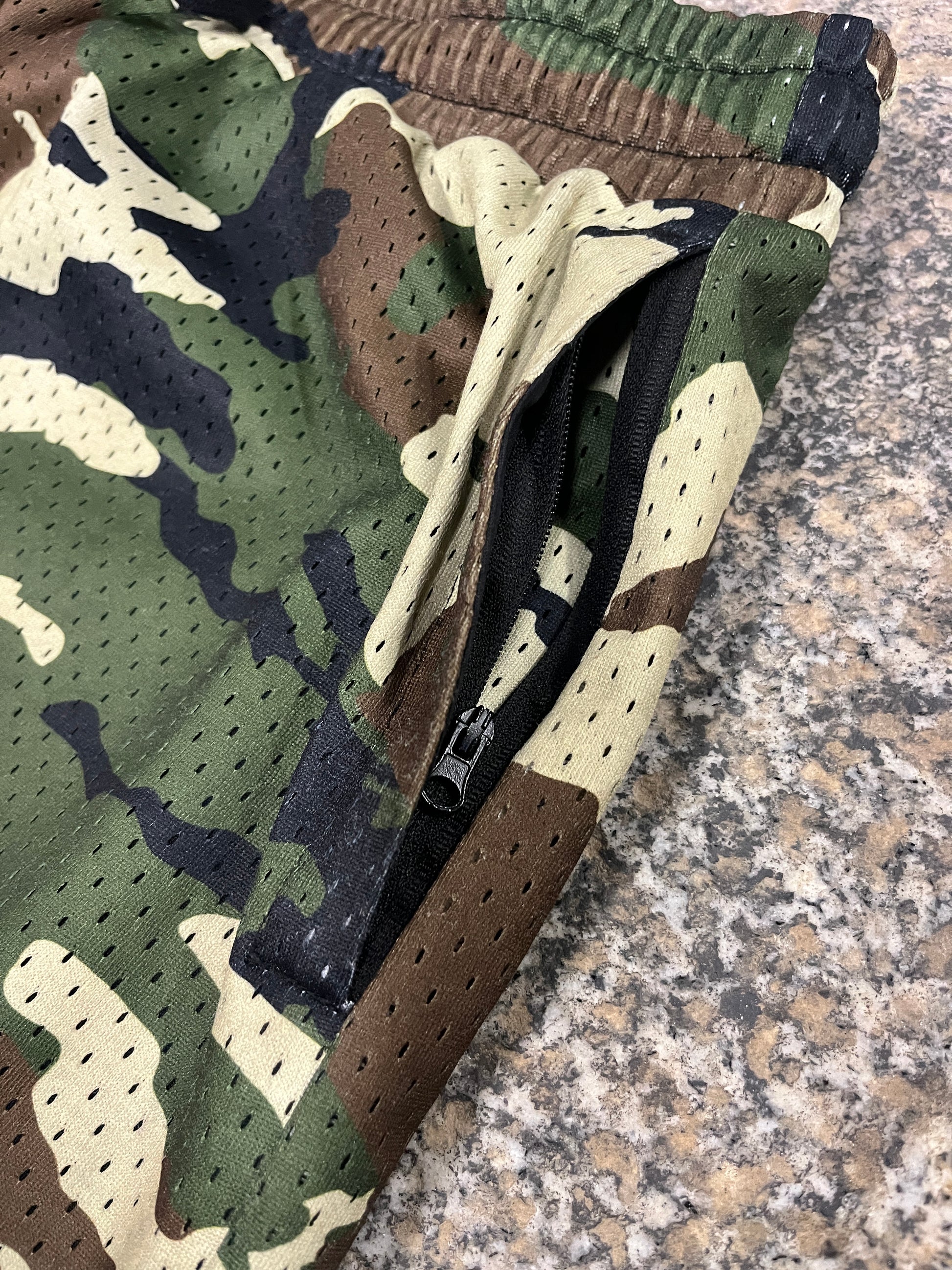 Camouflage-patterned bag with a brown strap on a textured surface