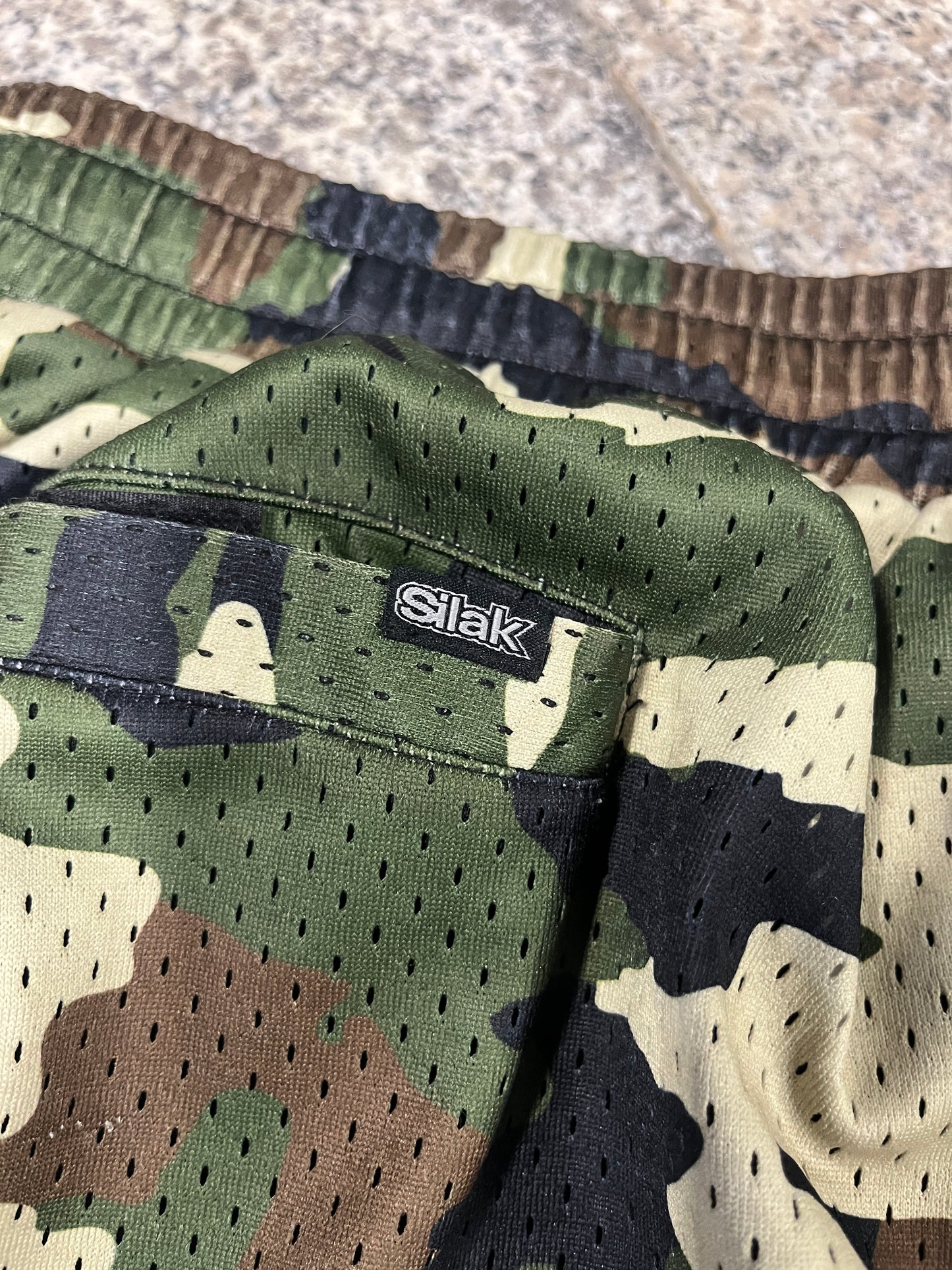 Camouflage-patterned fabric with a brand label on a textured surface